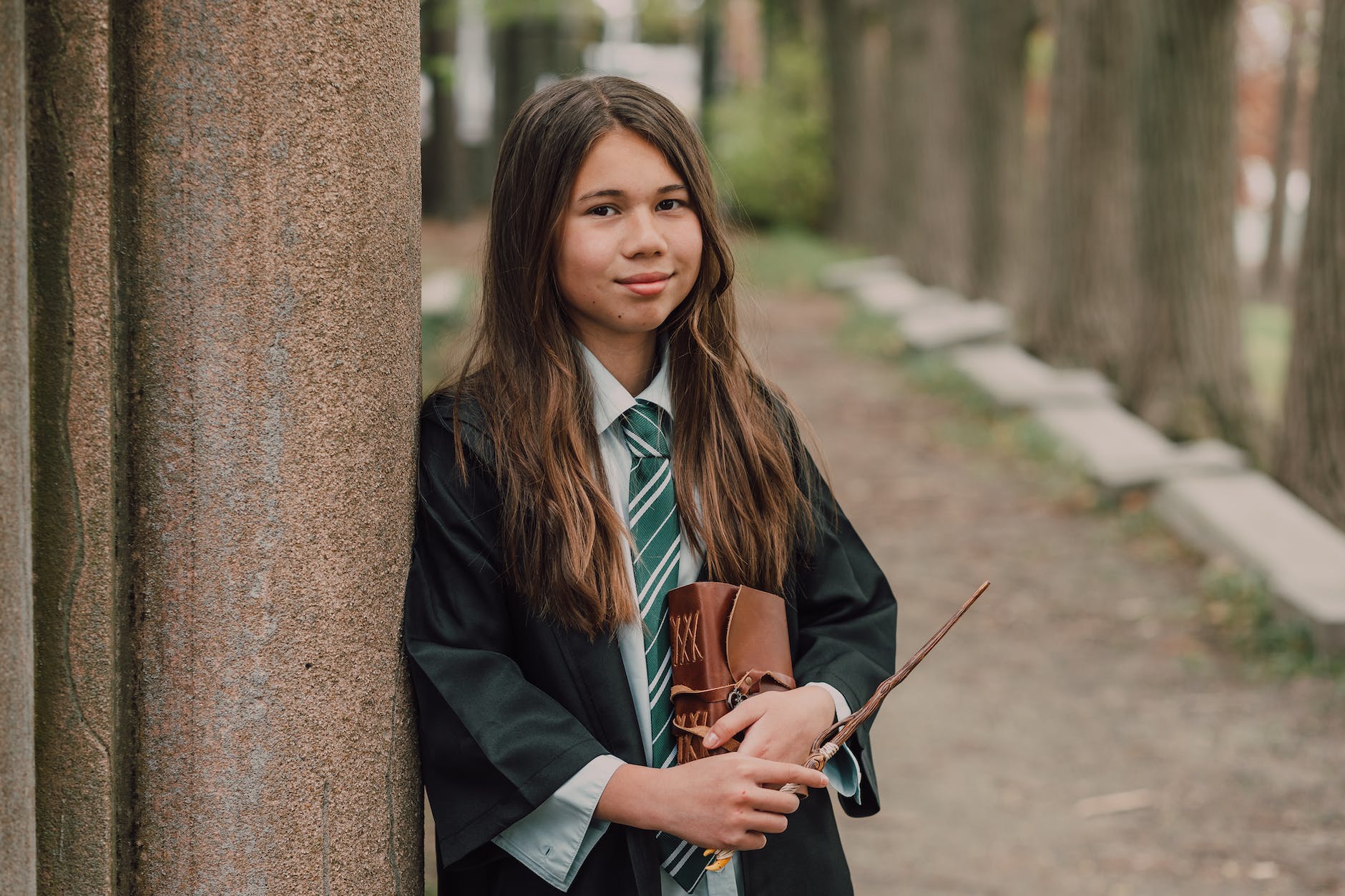a girl in black robe holding a wand and spell book