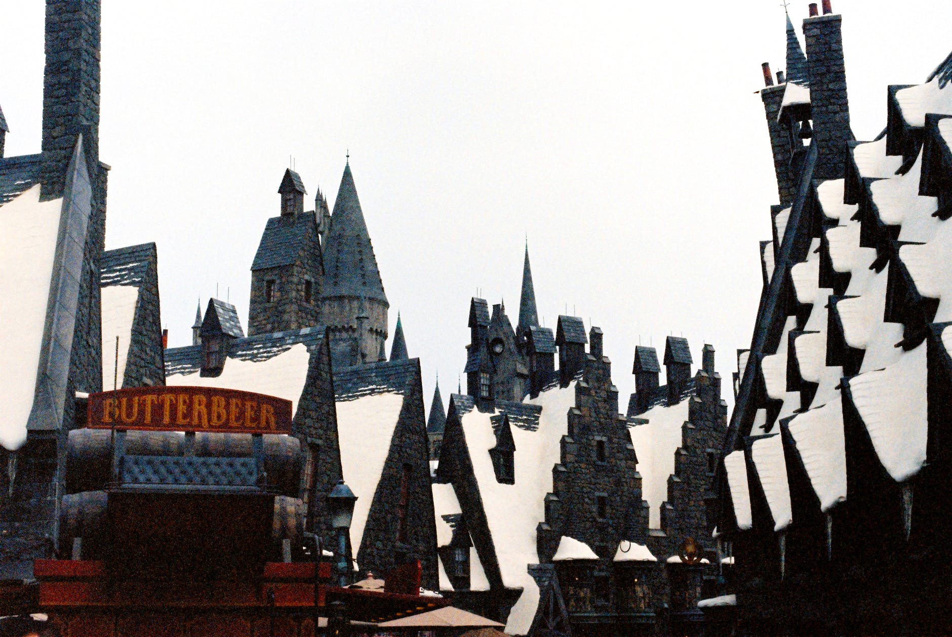 permanently snow covered roofs and a wagon with butterbeer barrels in the wizarding world of harry potter in orlando florida