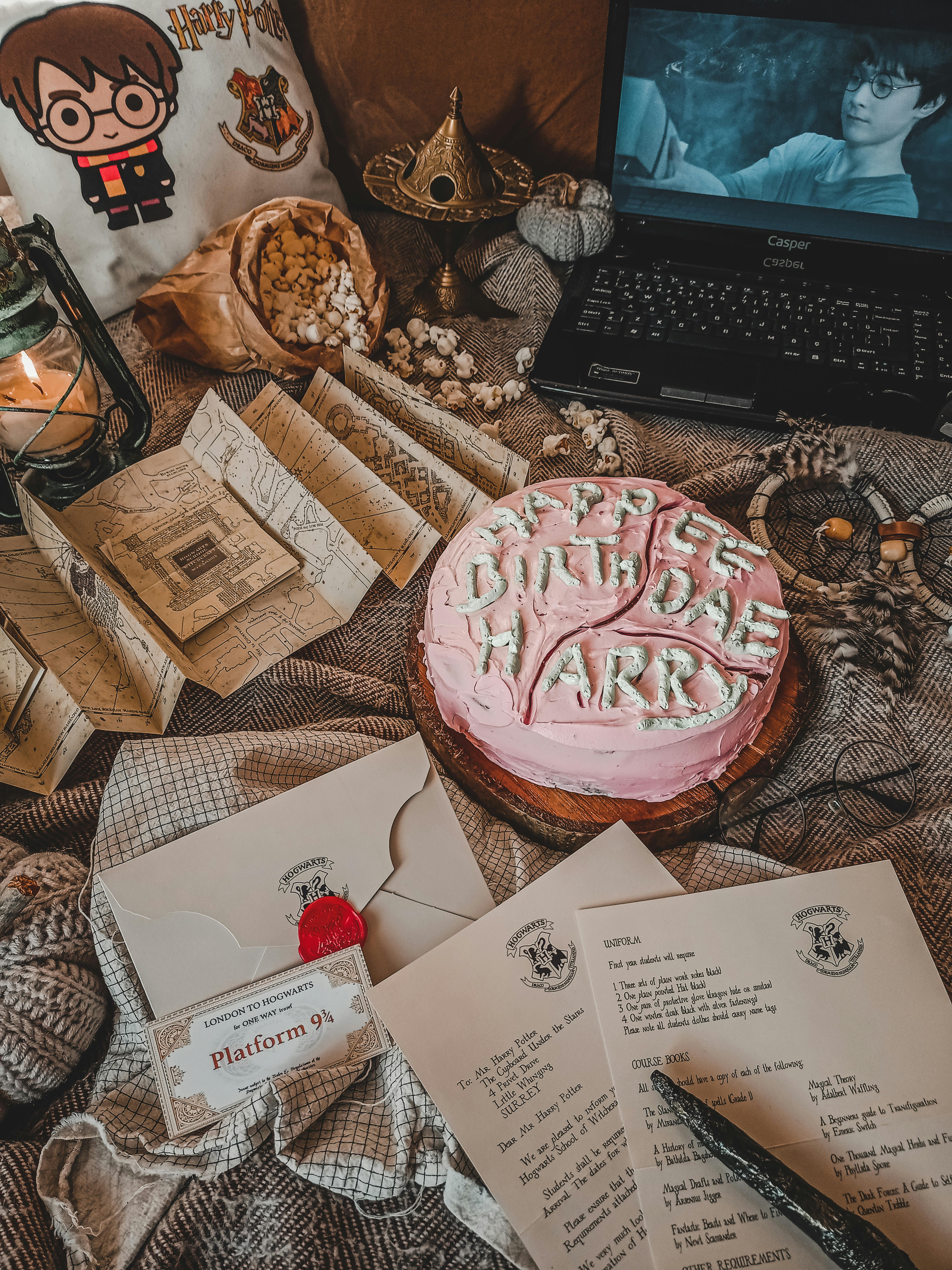 A cozy Harry Potter themed setting with a birthday cake, letters, and a laptop showing a movie scene.